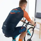 Mężczyzna na rowerze stacjonarnym, ćwiczący cardio. Na ekranie laptopa widać wirtualną trasę kolarską.