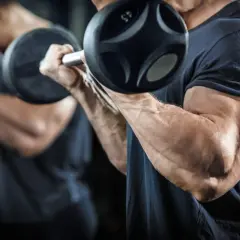 Mężczyzna ćwiczy bicepsy z hantlami, realizując swój trening split.