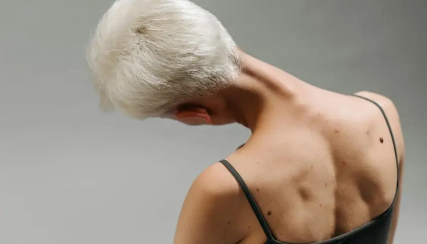 Widok z tyłu na kark i plecy osoby z krótkimi blond włosami. Widoczny mięsień dźwigacz łopatki.