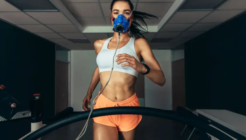 Kobieta w masce biegowa na bieżni, mierząca VO2max.