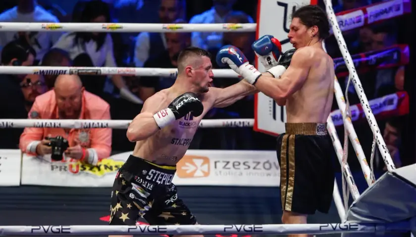 Dwóch bokserów walczy na ringu podczas babilon boxing show. Jeden z nich wyprowadza cios.