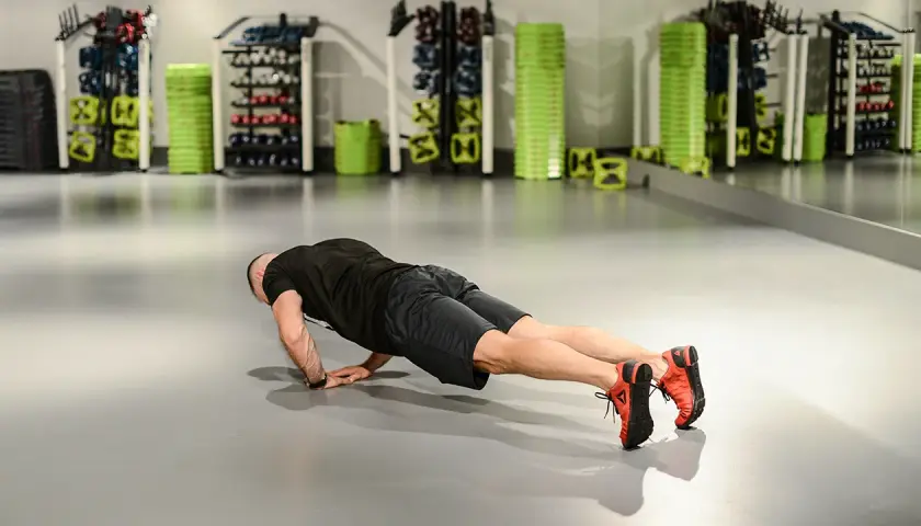 Mężczyzna wykonuje pompkę na triceps w siłowni.