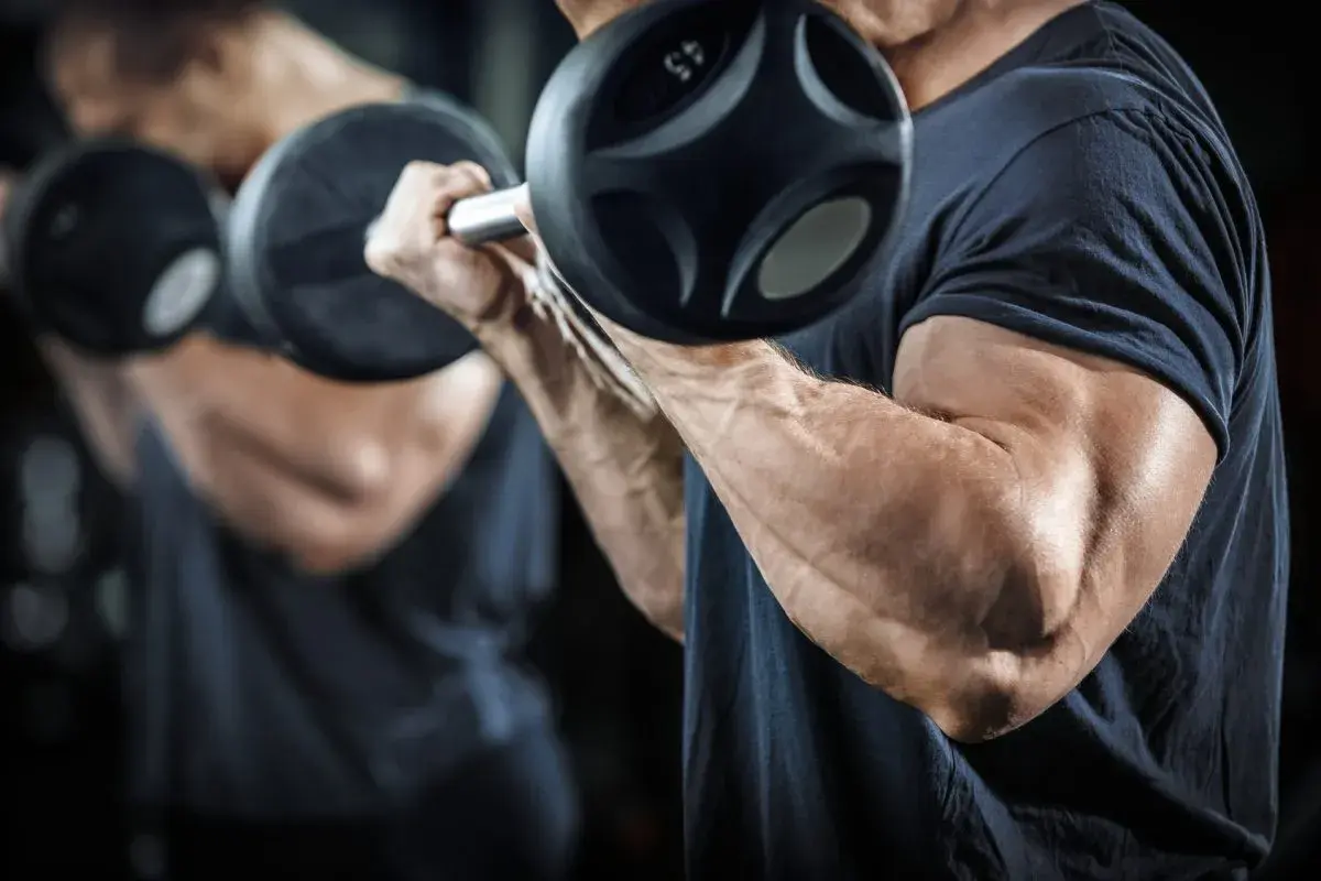 Mężczyzna ćwiczy bicepsy z hantlami, realizując swój trening split.