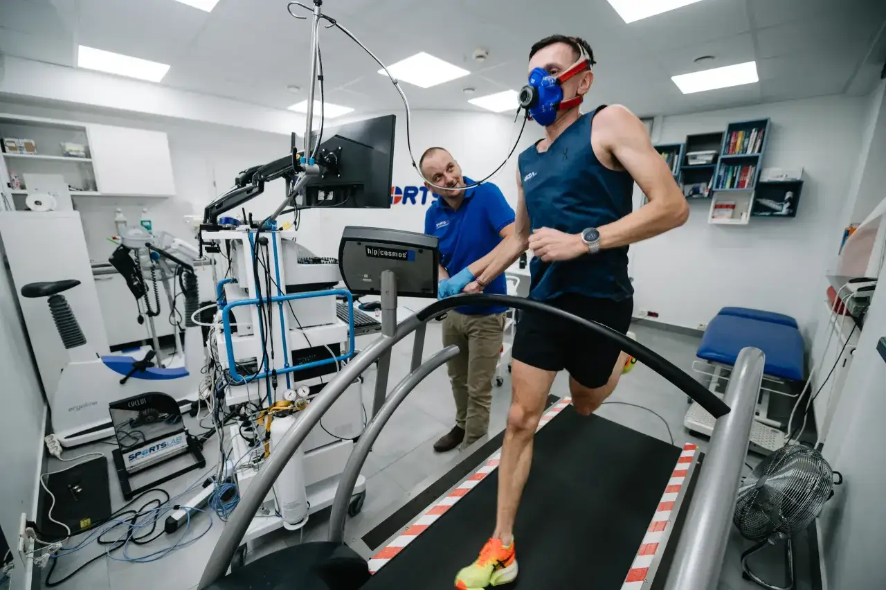Biegacz w masce testuje wydolność na bieżni, badając VO2max. To kluczowy wskaźnik kondycji.